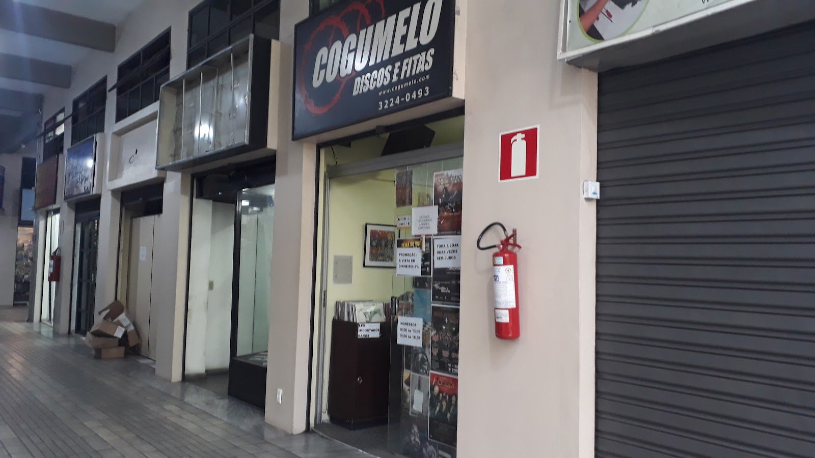 The Cogumelo Discos e Fitas shopfront in a Belo Horizonte arcade, a black sign with the red Cogumelo logo above an open glass door, LP bins and gig posters inside