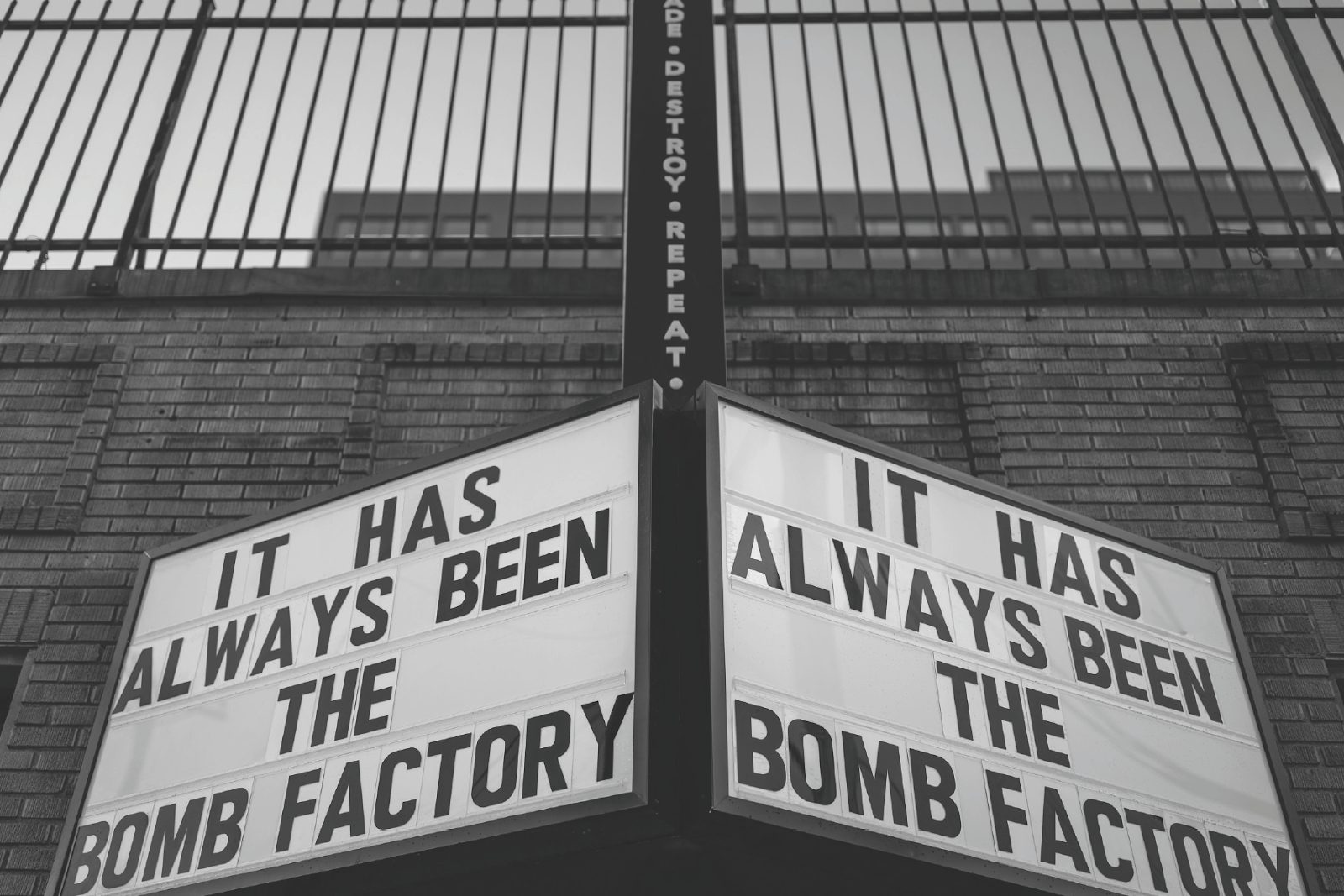 Black and white photo of the Bomb Factory's corner marquee, both sides reading It Has Always Been the Bomb Factory, against a brick wall