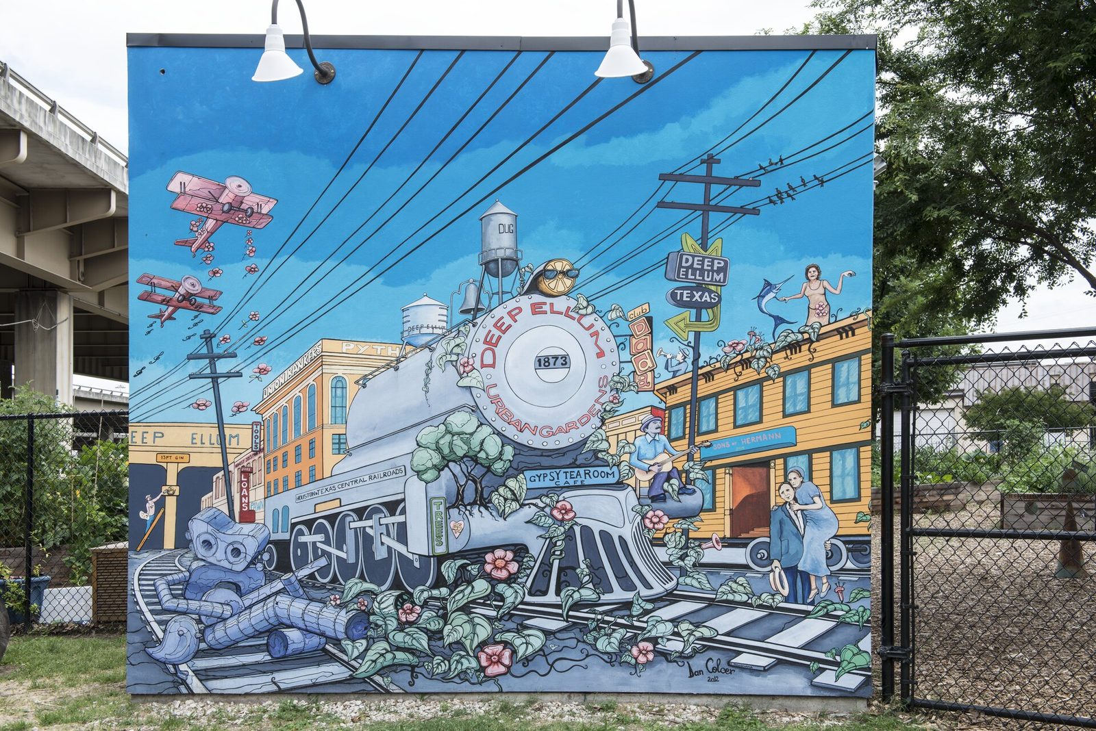 A painted mural in Deep Ellum showing a steam locomotive marked 1873, a Gypsy Tea Room sign, a seated guitarist and a couple in 1920s clothes in front of old brick storefronts
