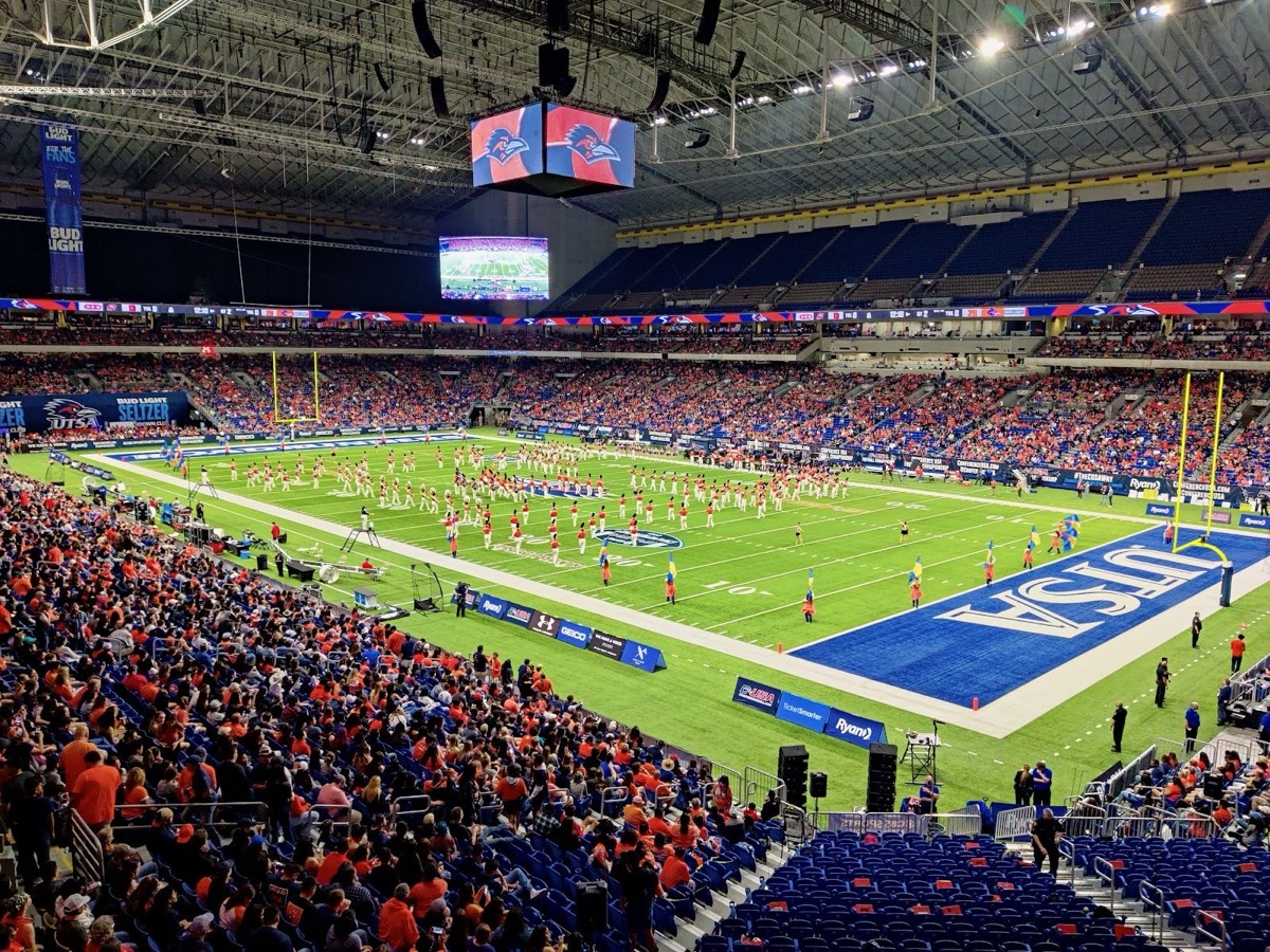 Inside the Alamodome in San Antonio: a packed lower bowl, a marching band on the football field and video boards hanging from the roof trusses
