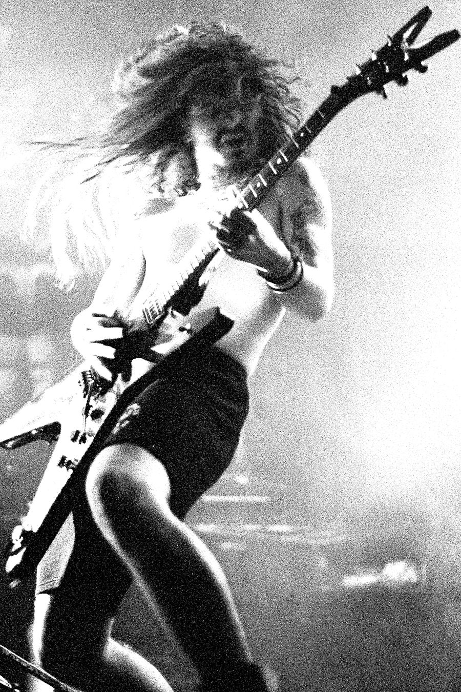 Black-and-white photo of Dimebag Darrell playing guitar onstage with Pantera, hair flying