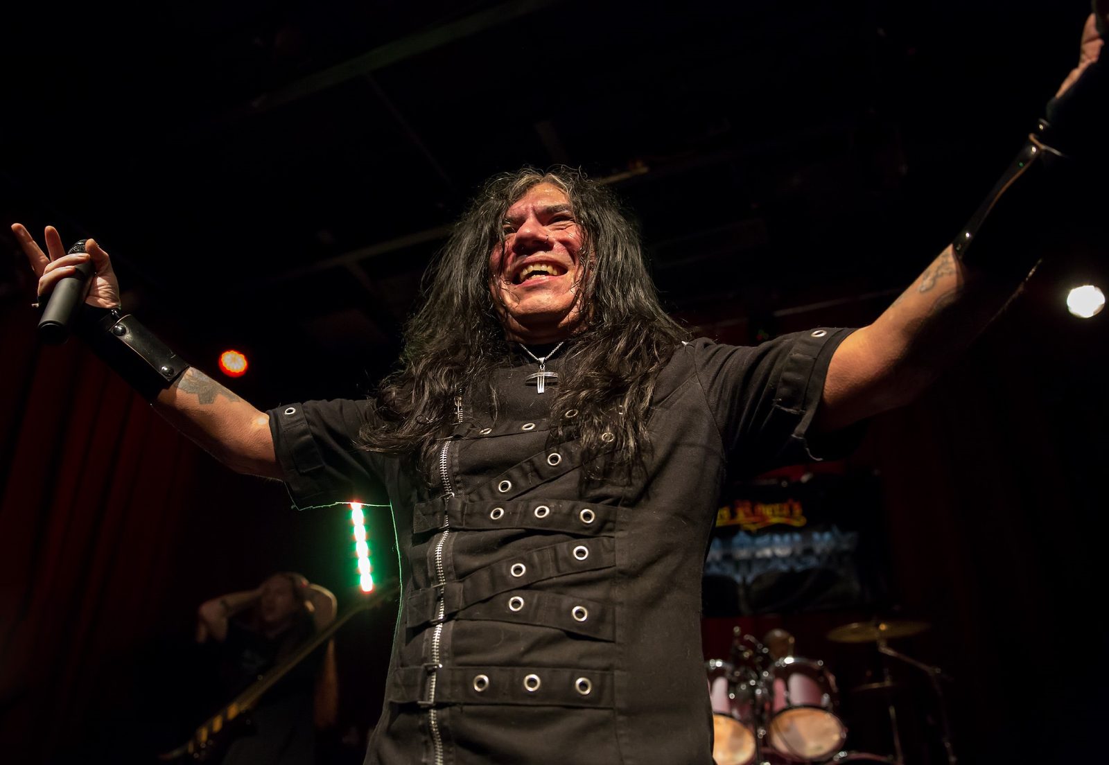 Helstar singer James Rivera onstage with arms outstretched, holding a microphone