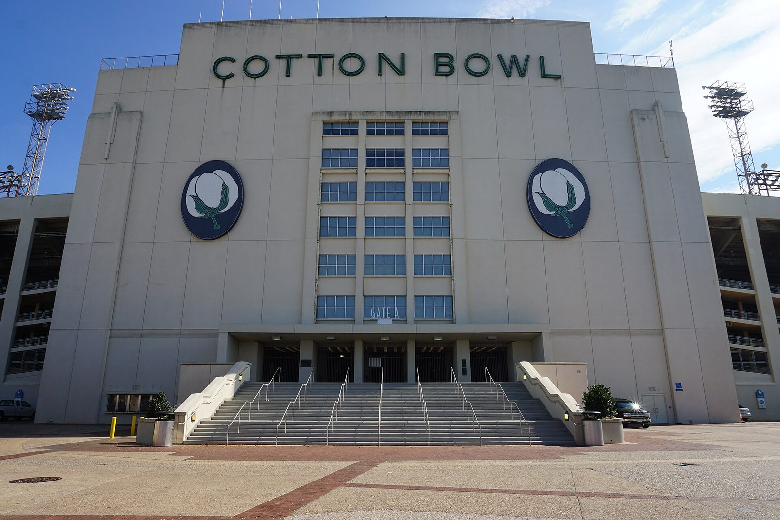 The pale Art Deco main facade of the Cotton Bowl, with COTTON BOWL in green letters across the top, two round cotton-boll emblems and a wide staircase up to Gate A