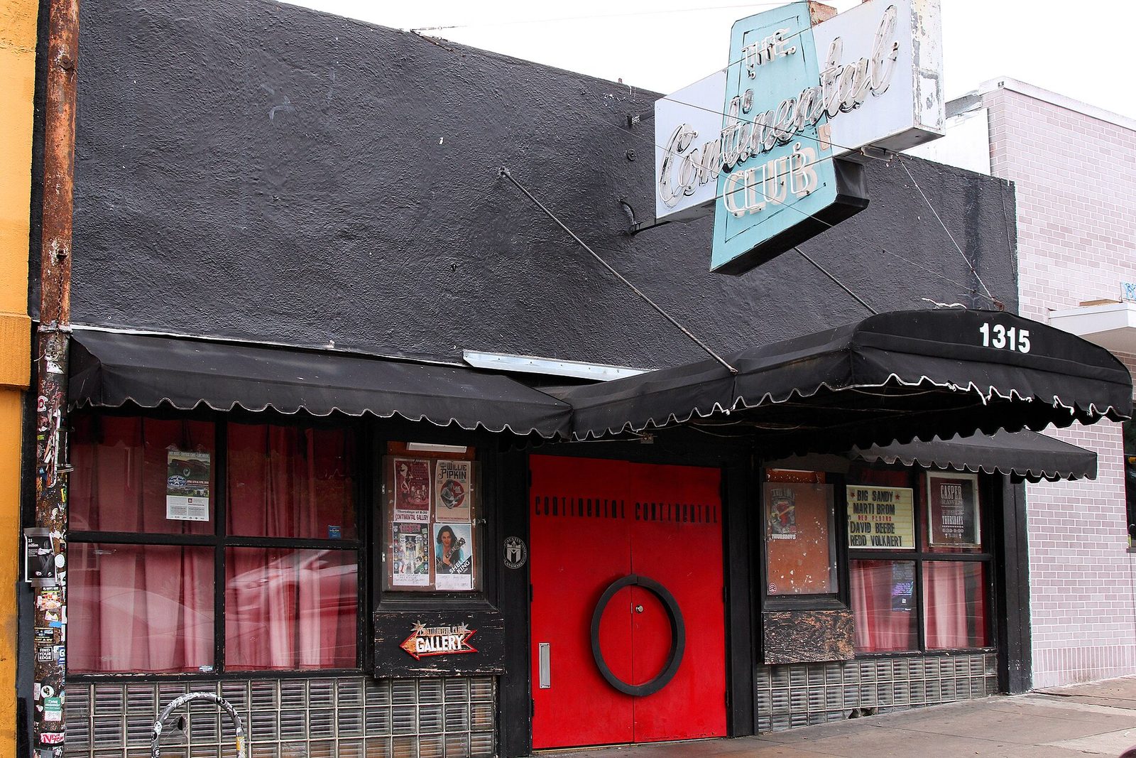 The Continental Club on South Congress in Austin by day, with its turquoise neon sign, black scalloped awnings, red double doors and the street number 1315